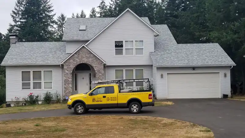 Yellow Gregg Roofing truck in the drive of a white two-storey house with a new grey roof