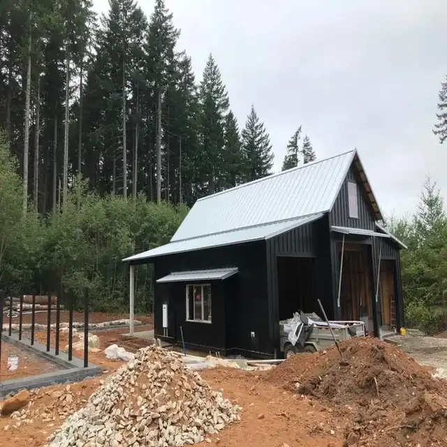 Black board-and-batten outbuilding with a standing-seam metal roof