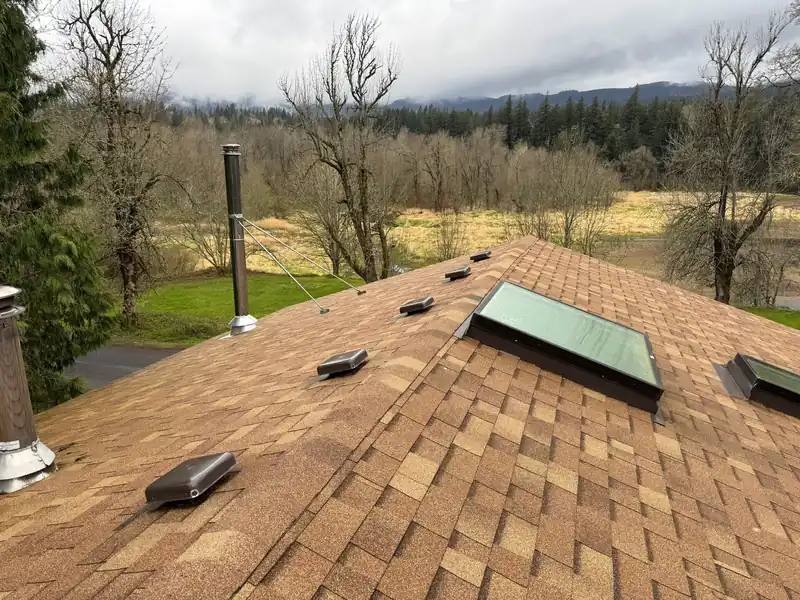 Brown laminated shingle roof with skylights and vents above a valley