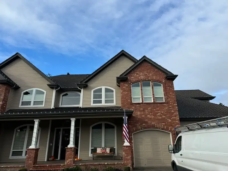 Brick and tan two-storey house with new shingles