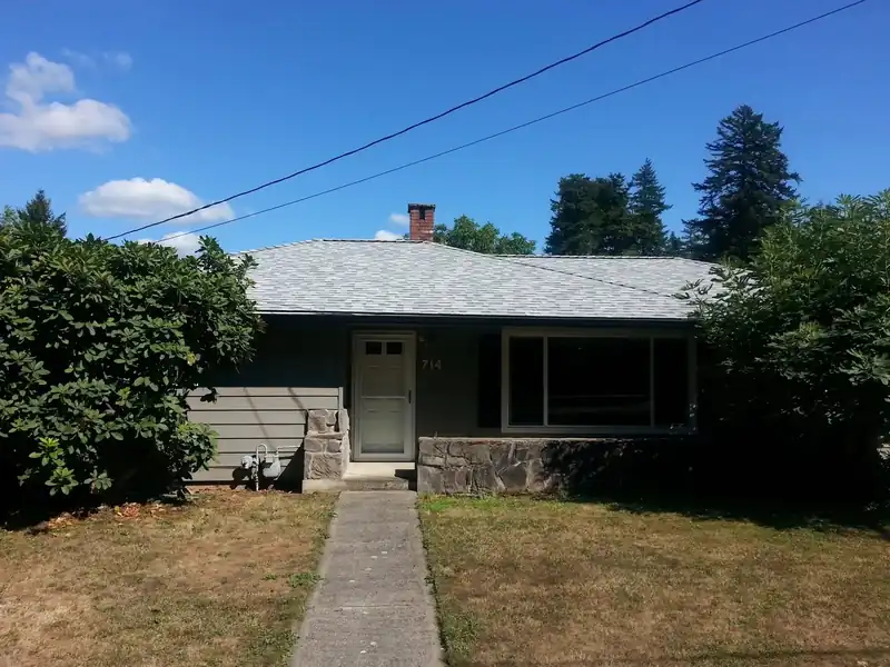Ranch house with a freshly shingled roof under tall firs