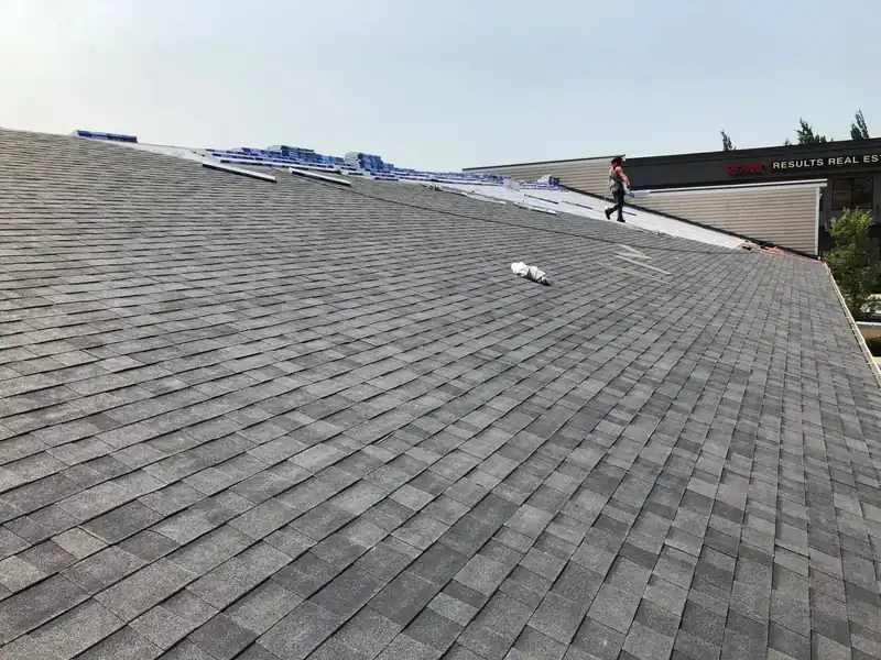 Crew working at the ridge of a grey shingle roof
